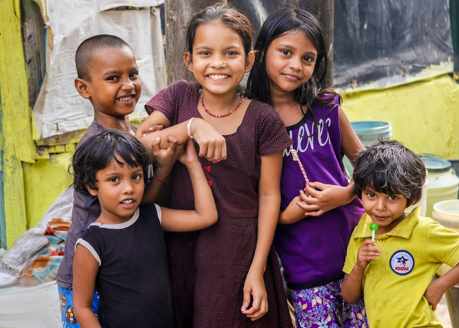 Children smiling together outside their homes